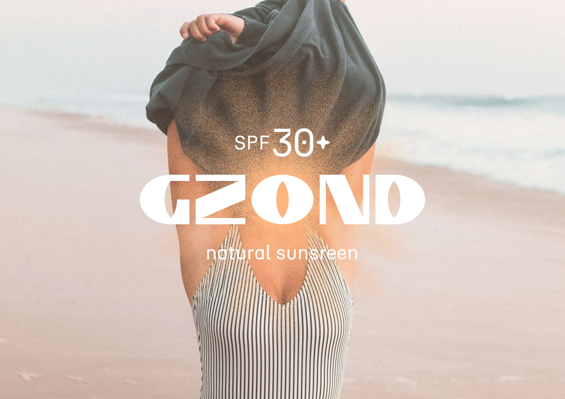 The wordmark and natural sunscreen line over a swimmer, the sun burning through the type